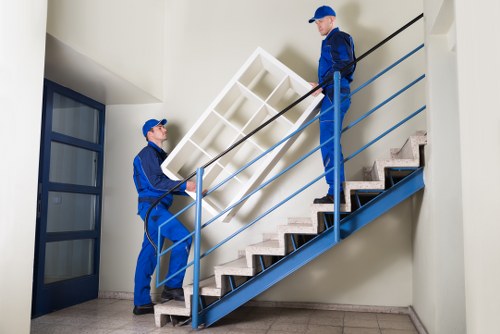 Removal crew carrying furniture through a Kensington townhouse staircase